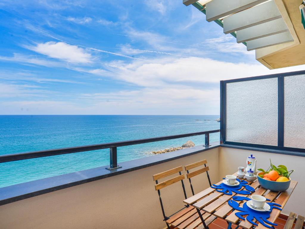 Un balcón con mesa y sillas y el mar. en La Casa del mare di Ginni e Virgi by Holiday World, en Bergeggi