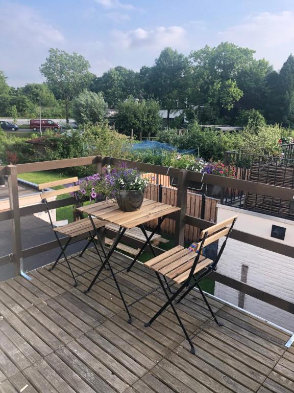 un tavolo e sedie in legno su una terrazza fiorita di Appartement aan de IJssel a IJsselmuiden