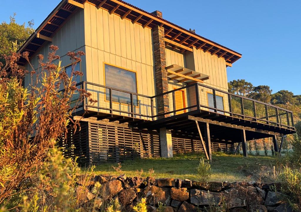 a large wooden house with a balcony on a hill at Taipas de Urupema - Vinícola e Pousada Boutique in Urupema