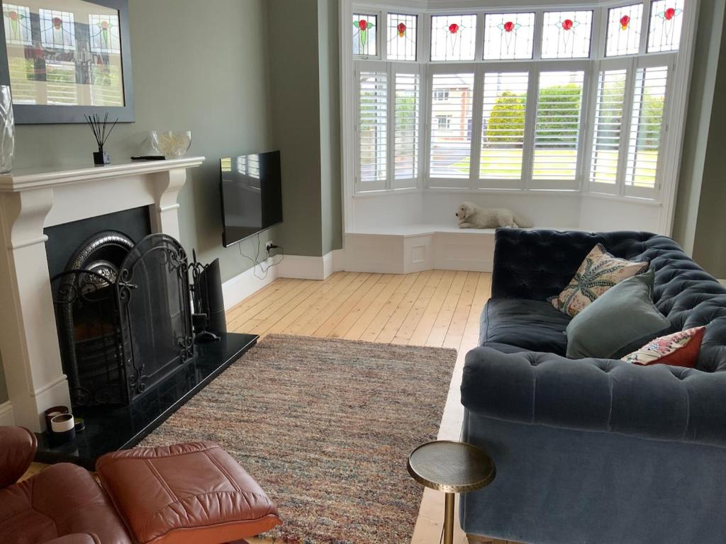 a living room with a blue couch and a fireplace at Period property Portrush in Portrush