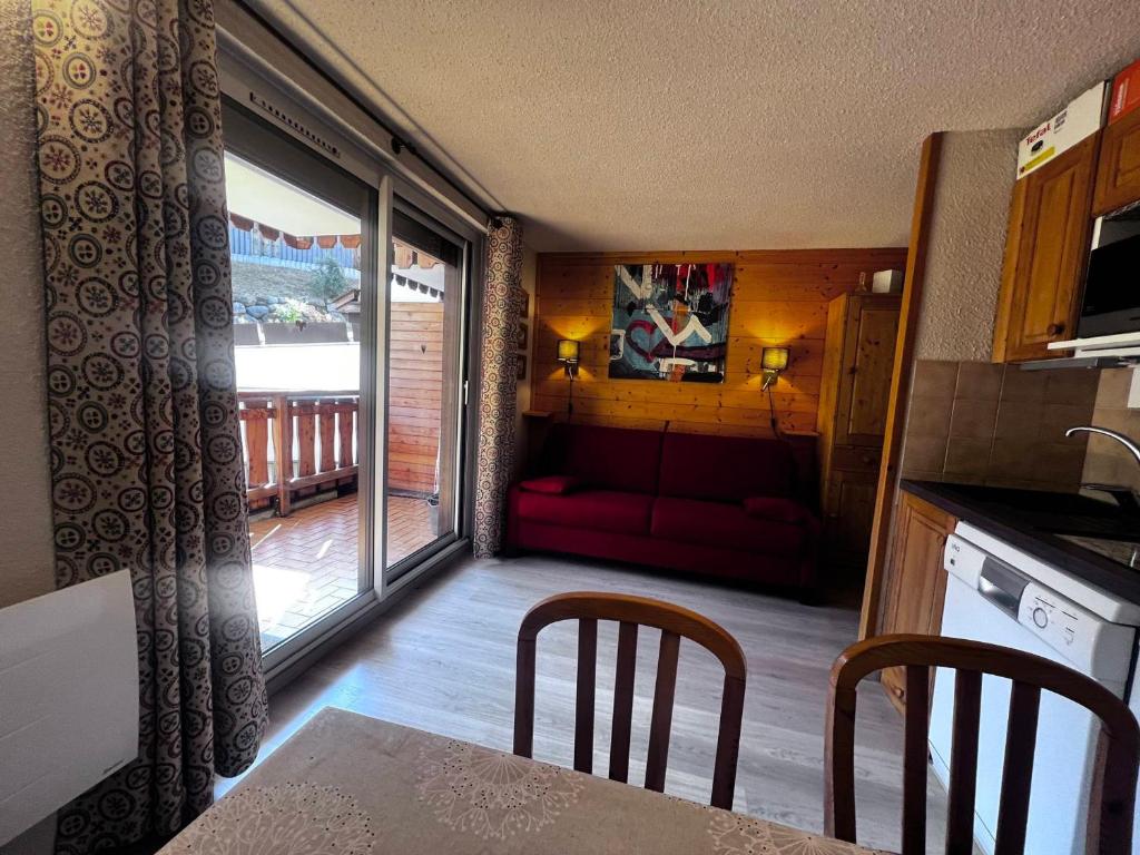 Il comprend une cuisine et un salon avec un canapé rouge. dans l'établissement Appartement Centre Village ★★★, Parking, WIFI, Pied des Pistes, Confort 4 pers - FR-1-437-14, à La Clusaz