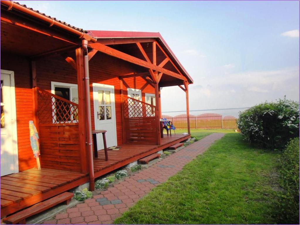 a small wooden cabin with a porch on a lawn at Domek Piaski Nad Morzem in Krynica Morska