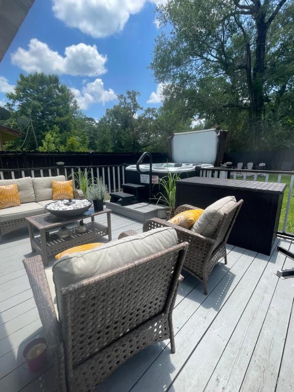 a patio with wicker chairs and a table at Tiny Home in Town-Hot Tub - Privacy Fence - Fire Pit - Kids Play Area & 15 minutes to the Bogue Chitto State Park in Franklinton