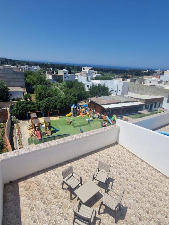 Raʼs al JabalRAS JEBEL APT route de la plage vue sur mer的一个带椅子的庭院和一个屋顶游乐场