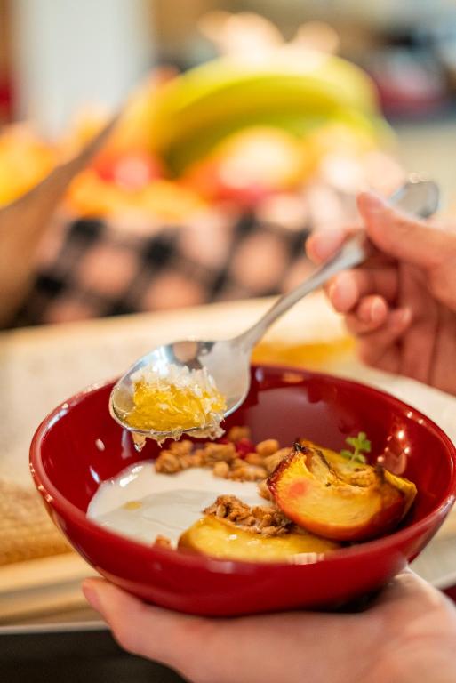 a person holding a red bowl of food with a spoon at La Genzianella Bormio in Bormio