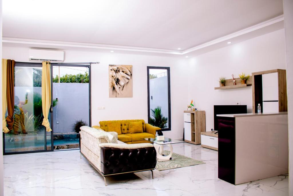 a living room with a yellow couch and a tv at Résidences Millenium Suites Yakro in Yamussukro