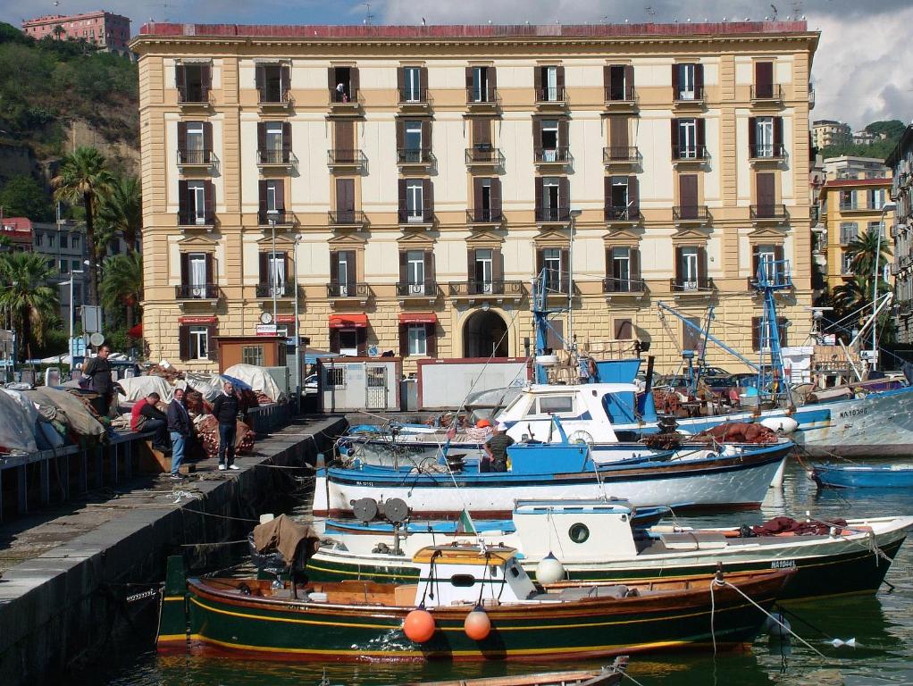 um grupo de barcos na água em frente a um edifício em Caracciolo 10 em Nápoles
