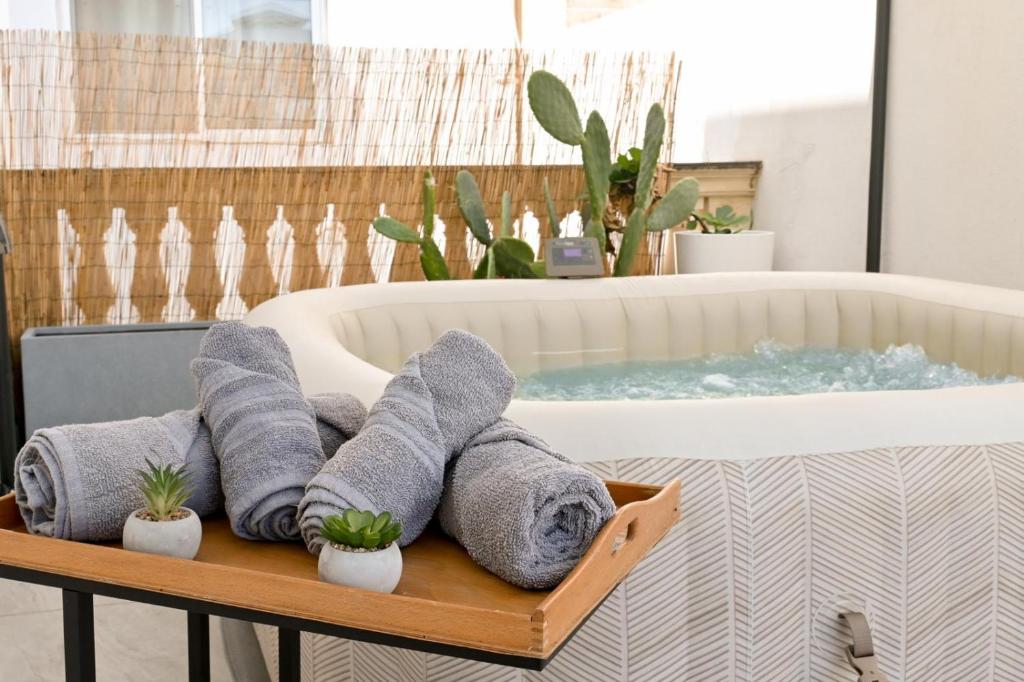 a pile of towels on a tray next to a bathtub at Vue Mer & Jacuzzi - Calme entre Valette et Sliema in Taʼ Xbiex