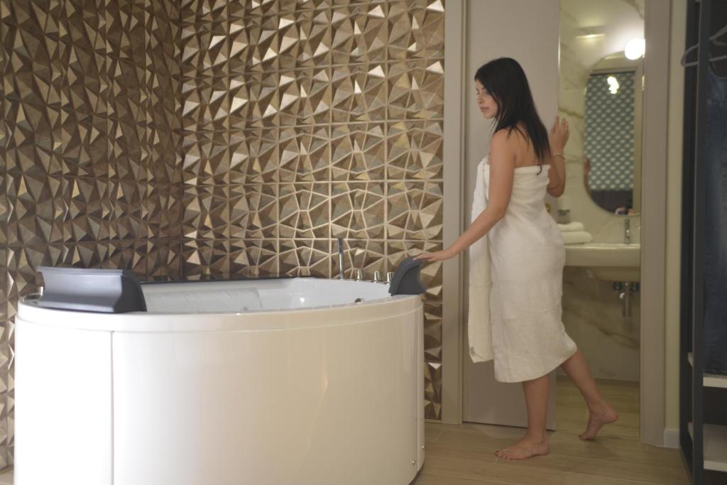 a woman in a white dress standing next to a bath tub at HT Room Spa & Suite in Brindisi