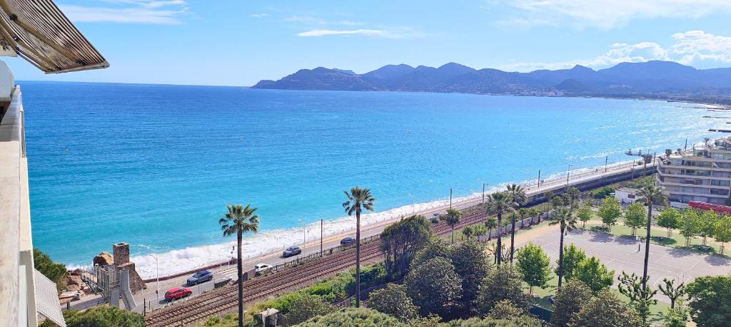 une vue sur une plage avec des palmiers et l'océan dans l'établissement Cannes Studio Vue mer Panoramique Château de la Mer, à Cannes