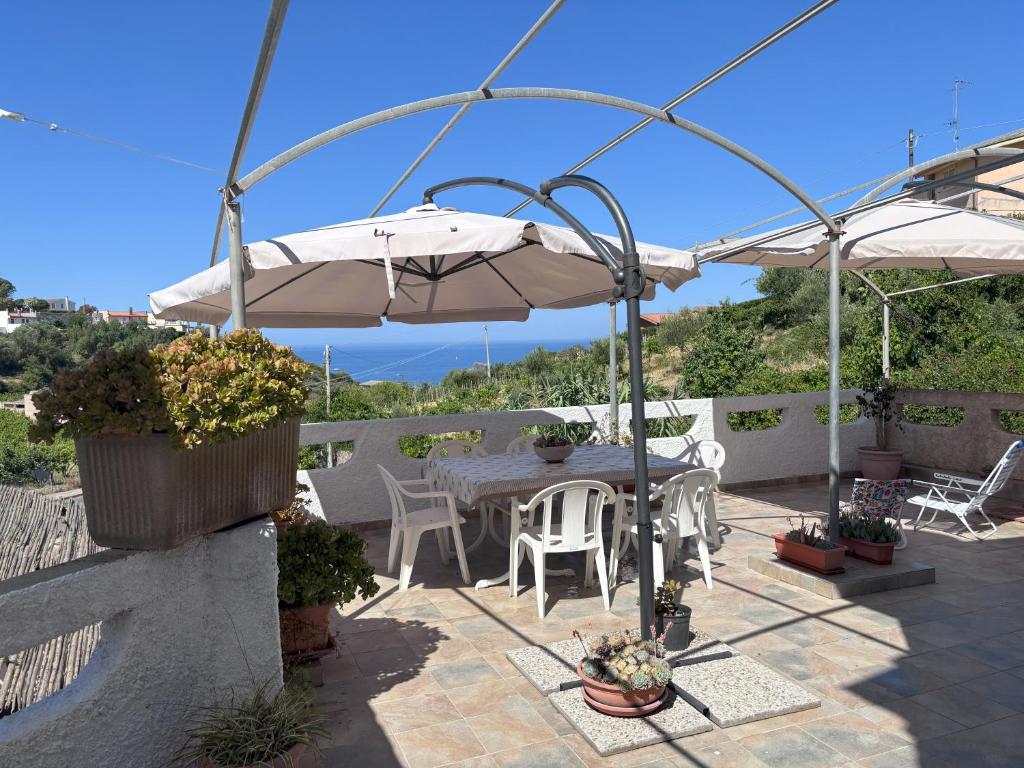 a patio with an umbrella and a table and chairs at Bosa appartamento Bouganville con vista mare ampio terrazzo in Magomadas