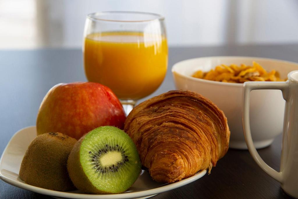 a plate of fruit with a croissant and a glass of orange juice at Park Hôtel & Appartements in Cholet