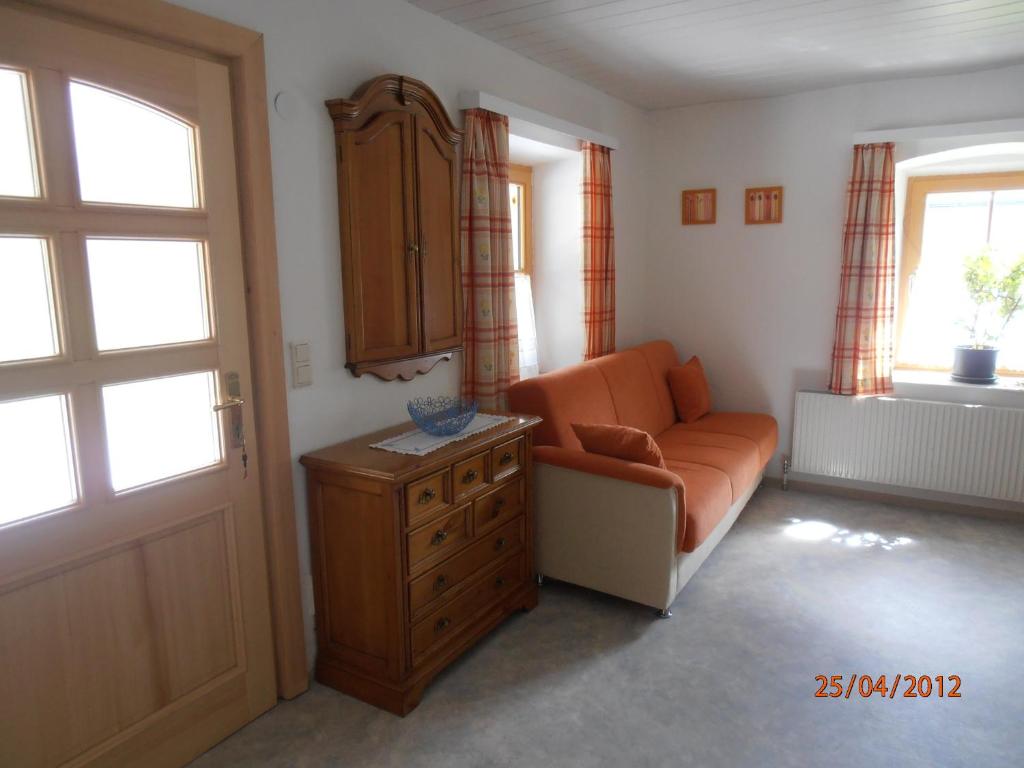a living room with an orange couch and a cabinet at Huberbauer in Johnsbach
