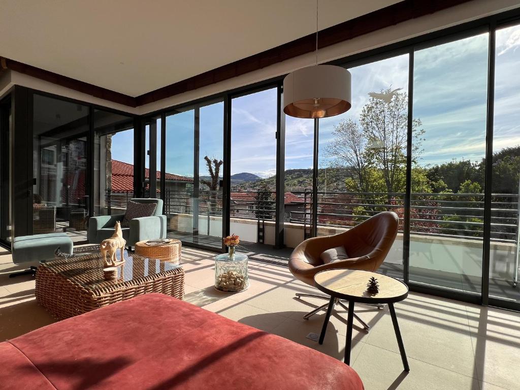 un salon avec un canapé, des chaises et des fenêtres dans l'établissement La Plâtrière, appartement classé 5 étoiles, avec garage en ville haute du Puy, au Puy-en-Velay