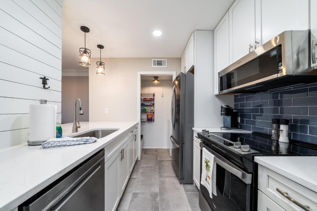 a kitchen with white cabinets and black appliances at 1307 Pelican Watch Villa in Seabrook Island