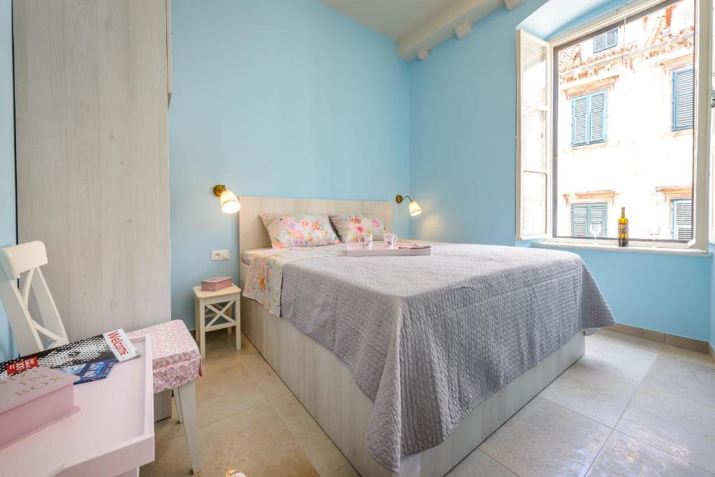 um quarto azul com uma cama e uma janela em Stradun View En Suite Rooms & Studio em Dubrovnik