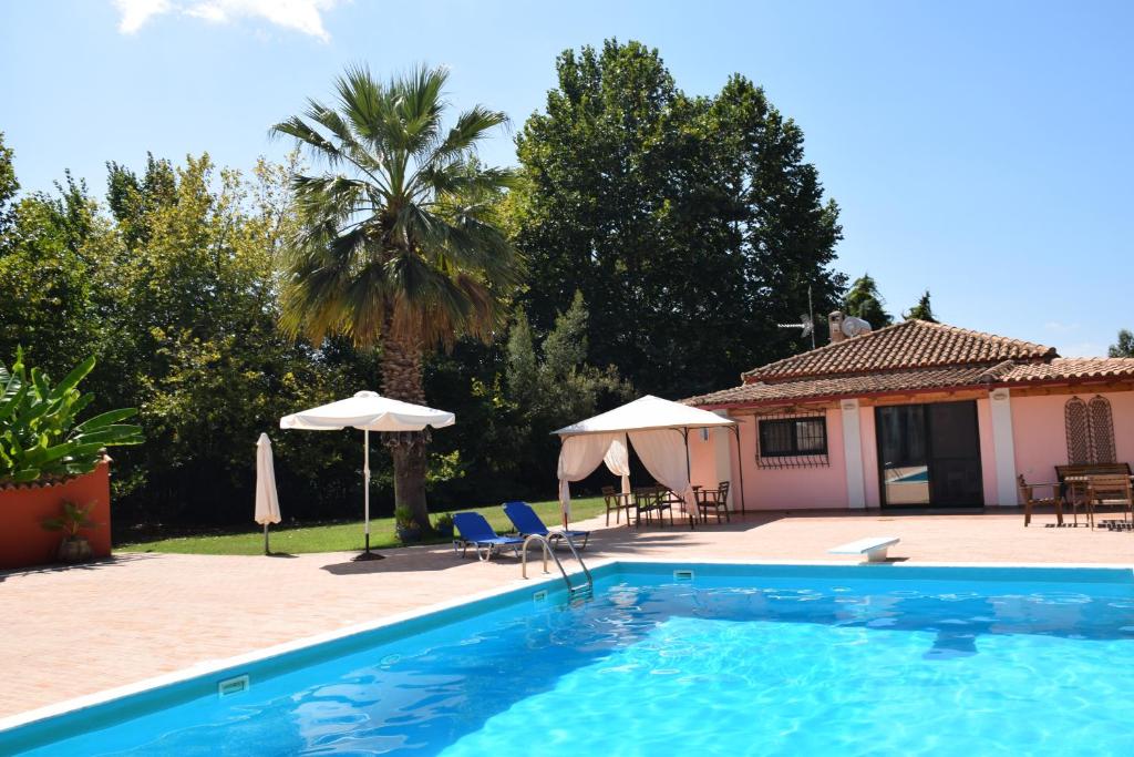 a swimming pool with chairs and umbrellas next to a house at Αρετή in Amaliás