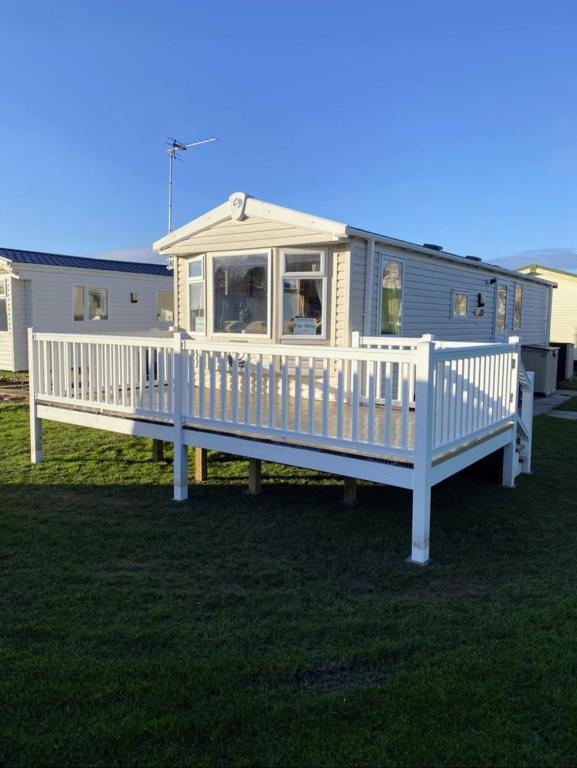 a mobile home with a porch and a white fence at The Retreat Gold - Lido Beach Prestatyn in Prestatyn