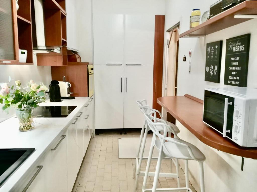 une cuisine avec des armoires blanches et un comptoir avec des tabourets dans l'établissement en centre ville magnifique pied a terre ran44, à Cannes