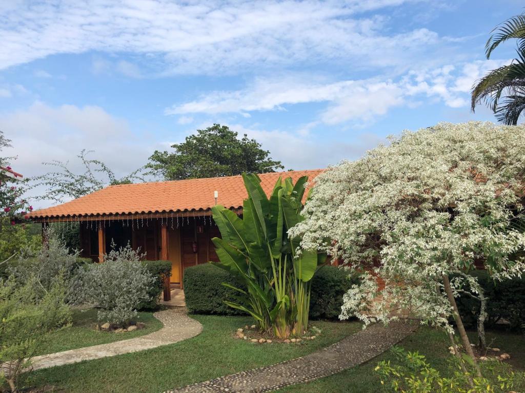 圣代佩德罗Pousada Estância Travessia的一座带花园和鲜花树的房子