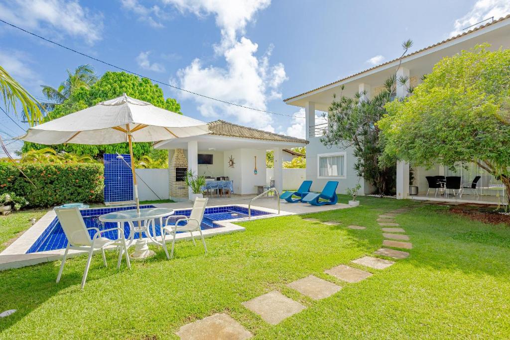 a backyard with a table and chairs and a pool at GB124 Linda Casa com 4/4 a 300m da Praia in Camacari