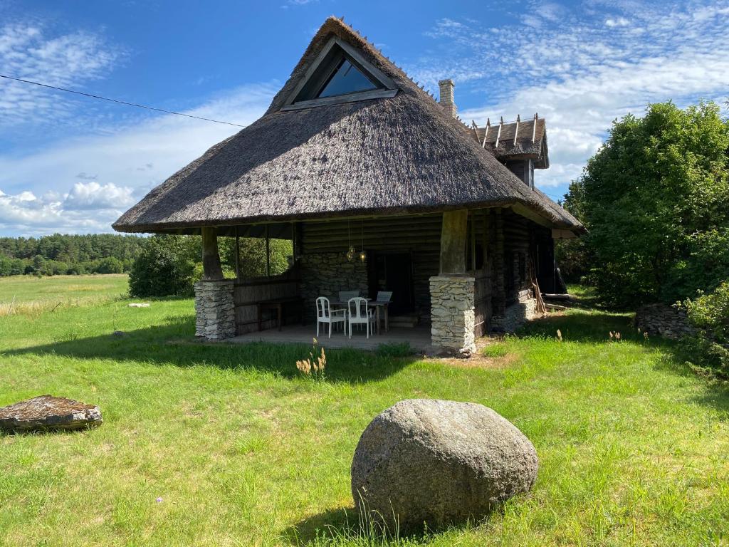 a log cabin with a grass roof on a field at Urikivi Holiday House in Orjaku