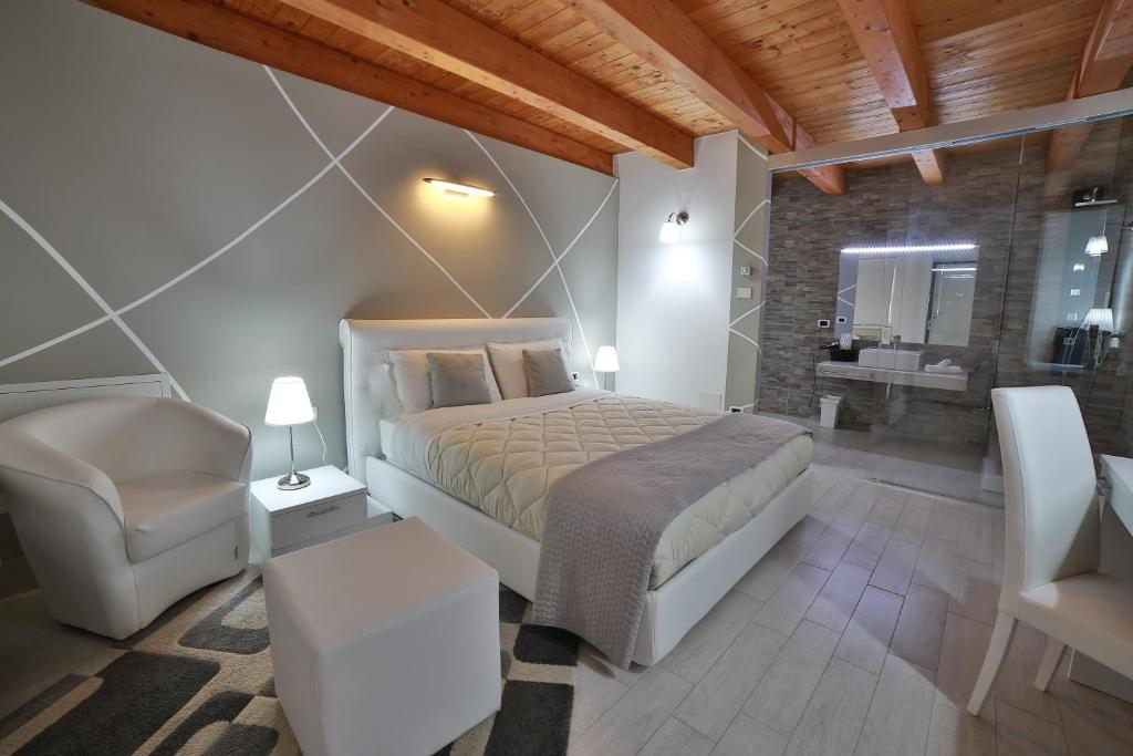 a bedroom with a bed and a chair and a bathroom at Villa Giulia Del Cavaliere in Castrovillari