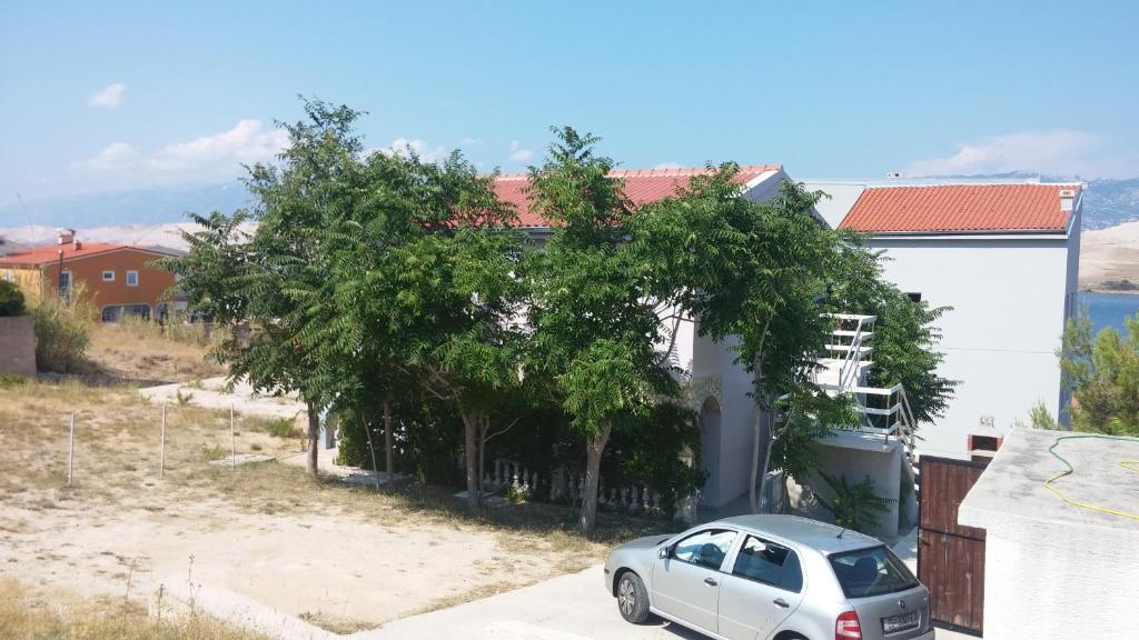 a car parked in front of a house with trees at Apartment Twins in Pag