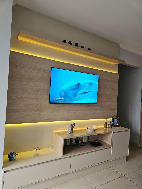 a living room with a flat screen tv on a wall at Apartamento 1 km da praia com ar e garagem in Vila Velha