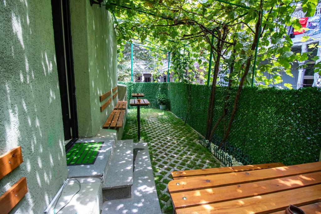 two benches sitting next to a green wall at Green Garden Guesthouse in Tbilisi City