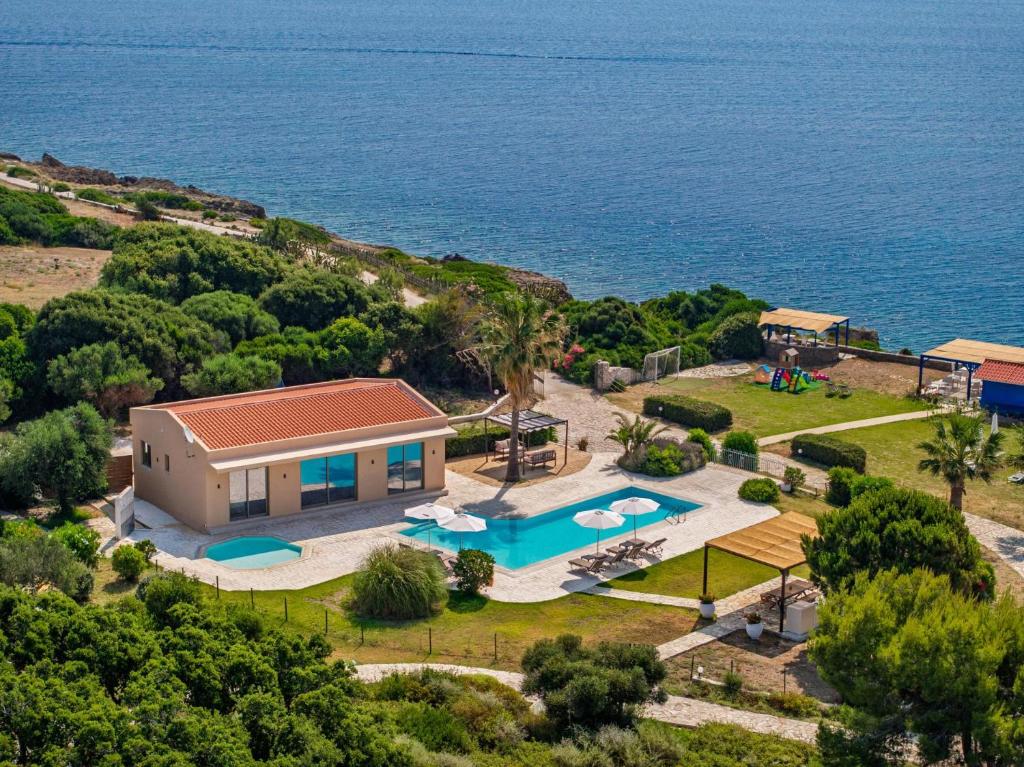 an aerial view of a house with a swimming pool and the ocean at Villa Ismini Periyali in Vasilikos