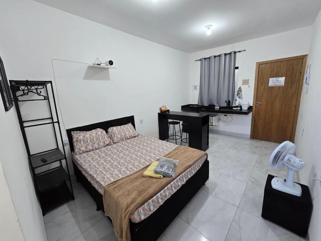 a bedroom with a bed and a small room with a table at Flat completo a 21 minutos da BR-153 in Aparecida de Goiania