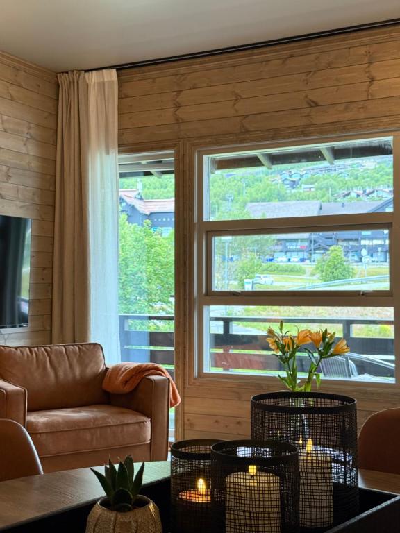 a living room with a couch and a large window at Geiloholtet central city apartment in Geilo