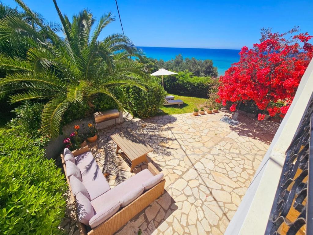 a patio with lounge chairs and the ocean in the background at Corfu Glyfada Beach Apartment in Glyfada