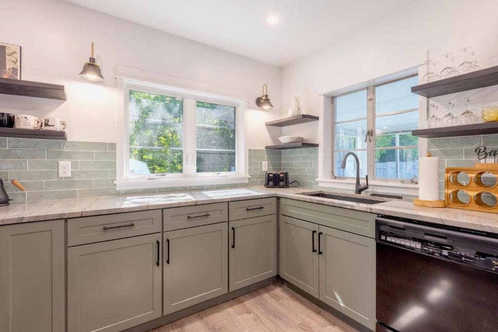 a kitchen with white cabinets and a sink and windows at Relaxation Station - Hot tub and scenic location downtown South Haven in South Haven