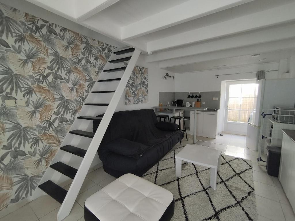 - un salon avec un canapé noir et un escalier en colimaçon dans l'établissement La Jarne bis, à La Jarne