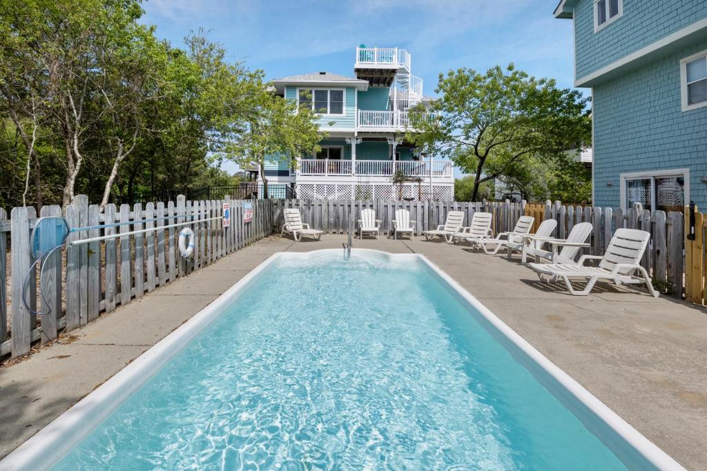 a swimming pool with chairs and a house at Dream23 in Corolla
