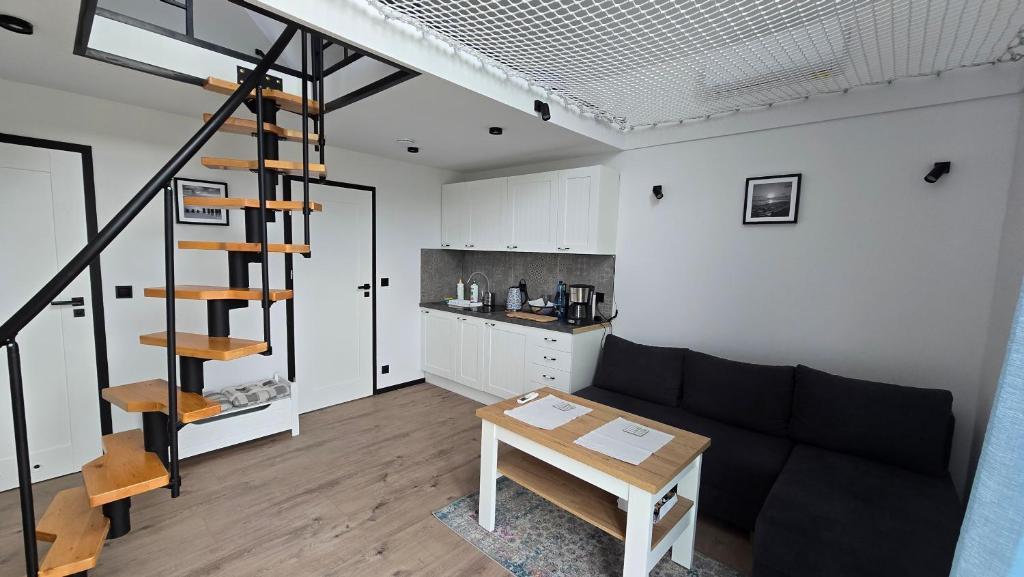 a living room with a black couch and a kitchen at Baltic Barns Storm in Wytowno