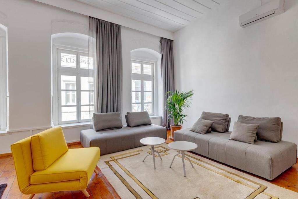 a living room with two couches and a yellow chair at Kois Loft in Ermoupoli