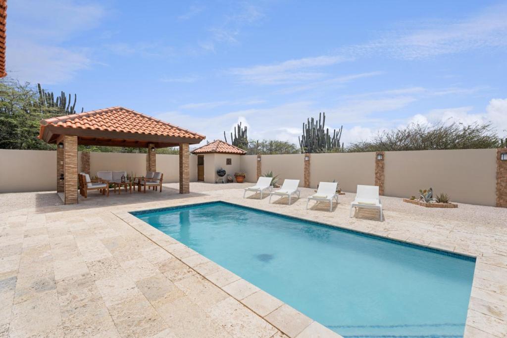a swimming pool with chairs and a gazebo at NEW 3BR 2BA Private Villa with Spacious Garden in Noord