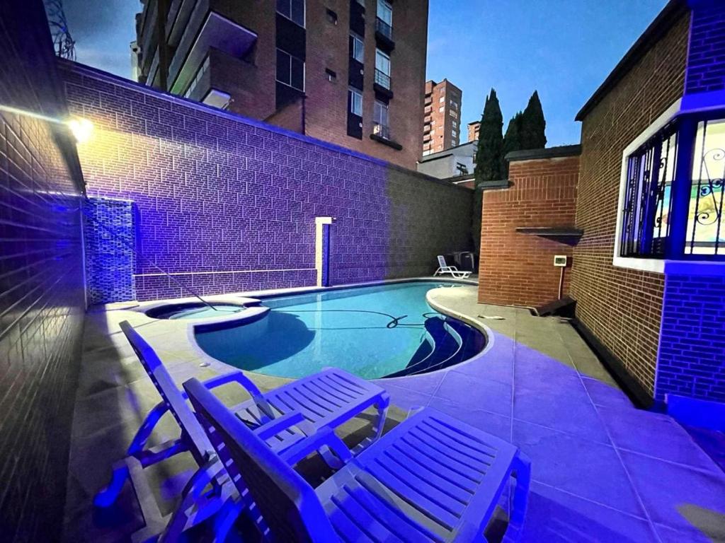 メデジンにある5BR Poblado 80s Mansion with Private Pool ACの建物の隣にスイミングプール(ラウンジチェア2脚付)