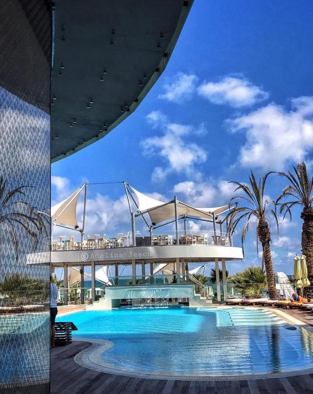 a view of a swimming pool with a bridge and palm trees at White Tower Apart Hotel in Mamaia