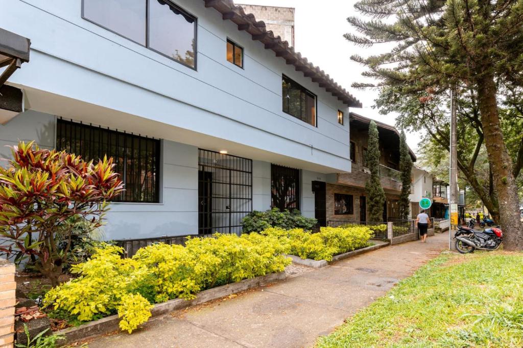 a white building with yellow flowers next to a sidewalk at L3 9BR Laureles House Rooftop 2 Jacuzzis AC in Medellín