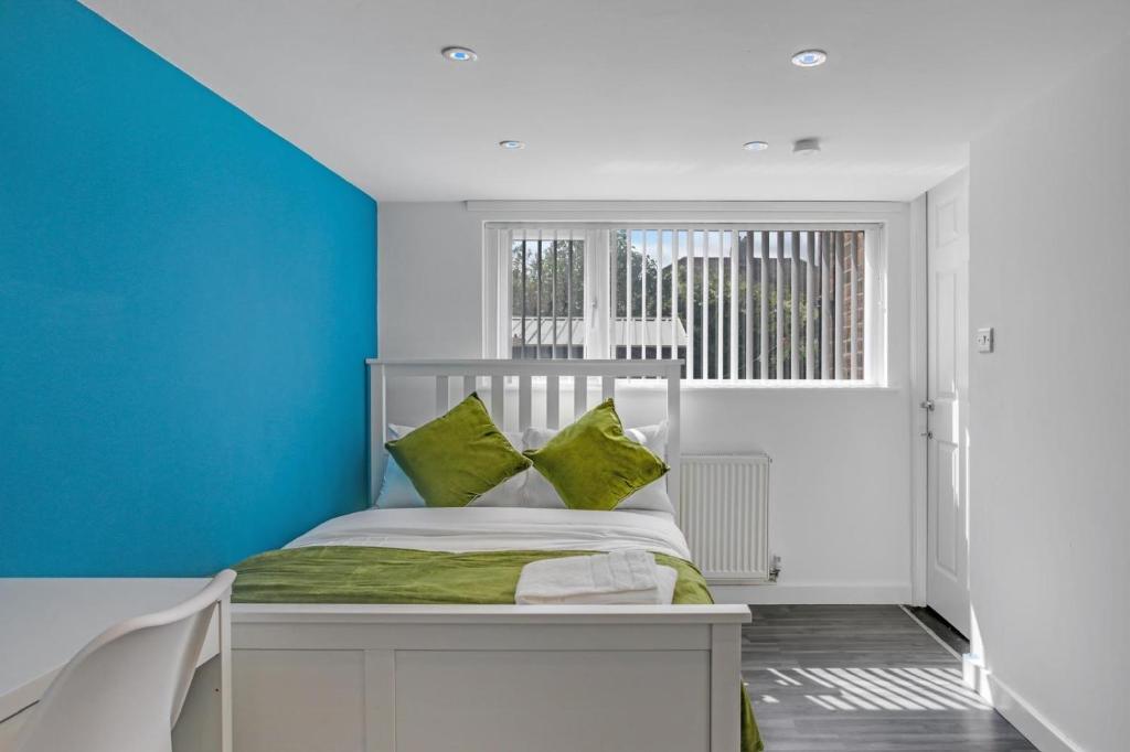 1 dormitorio con paredes azules y 1 cama con almohadas verdes en Luxury 5-bedroom home in Newcastle, en Longbenton