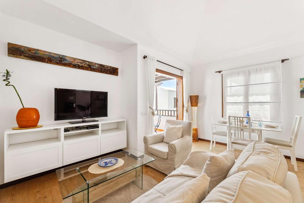 een woonkamer met een bank en een tv bij El Nido Seafront Hideaway by Bayside in Playa Honda