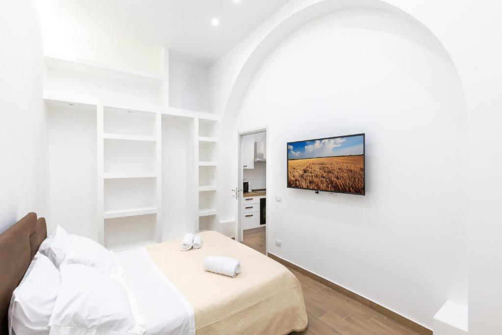 パレルモにあるLuxury Royal Houseのベッドと壁にテレビが掛かった寝室