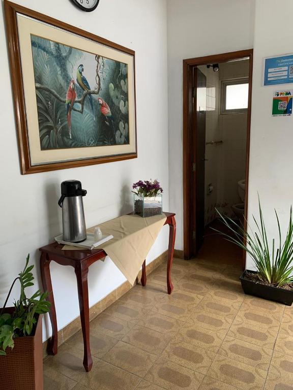 una habitación con una mesa y una foto en la pared en Hotel Carioca Palace, en Pindamonhangaba