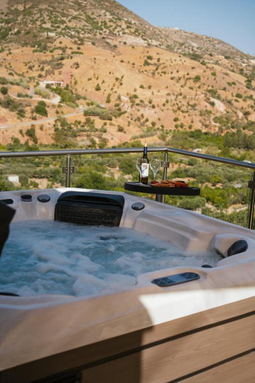 a jacuzzi tub with a bottle of wine and a hill at Mythos House in Episkopi Pafou