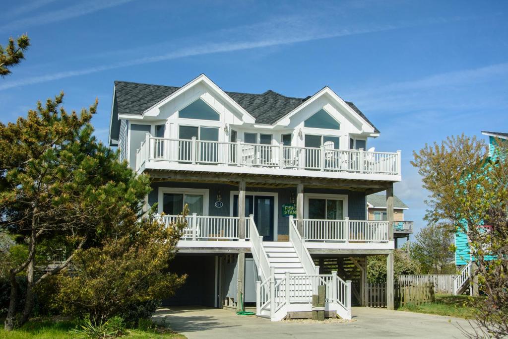a large house with a white deck and stairs at Fish Tank in Corolla