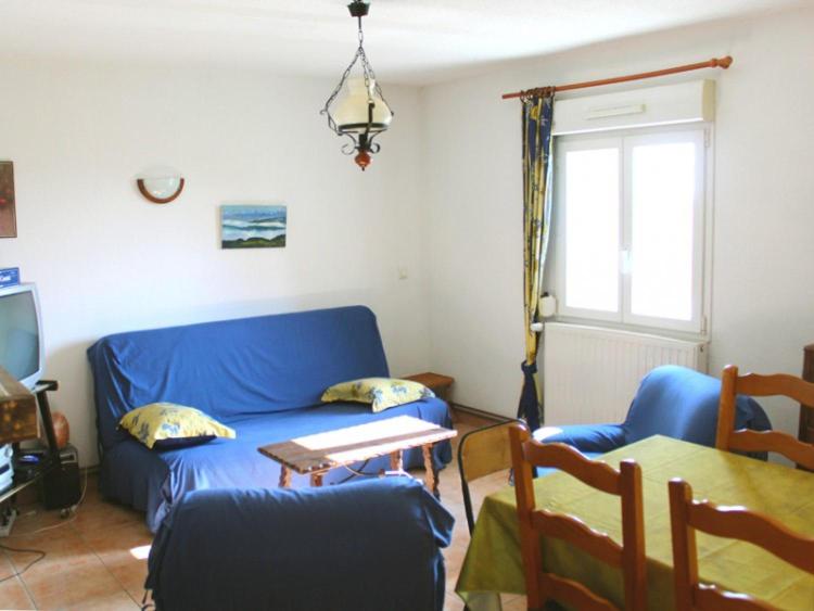 a living room with a blue couch and a table at Ferme Pédagogique " L'Bout d'Chemin" in Genevreuille